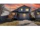 Charming two-story home with a two car garage and manicured front lawn set against a colorful sunset sky at 5436 S Versailles Way, Aurora, CO 80015