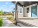 Covered front porch with stone pillar and light blue front door with a view of the front yard at 9700 E 63Rd Pl, Denver, CO 80238