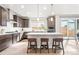 Bright, modern kitchen with dark cabinets, stainless steel appliances, and a central island with seating at 9700 E 63Rd Pl, Denver, CO 80238