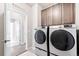 Laundry room with a side-by-side washer and dryer and overhead cabinets at 9700 E 63Rd Pl, Denver, CO 80238