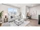 Comfortable living area with a gray sofa, stylish decor, large windows, and an adjacent desk space creating a versatile room at 9700 E 63Rd Pl, Denver, CO 80238