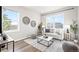 Bright living room featuring large windows, a gray sofa, modern decor, and wood-look floors offering an open, airy feel at 9700 E 63Rd Pl, Denver, CO 80238