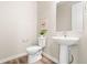 Clean powder room with white pedestal sink, toilet, and decorative mirror at 9700 E 63Rd Pl, Denver, CO 80238