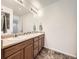 Bathroom with double sinks, wood cabinets, and a large mirror at 18241 E 47Th Dr, Denver, CO 80249