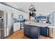 Modern kitchen with stainless steel appliances, a blue island, white cabinets, and hardwood flooring at 1929 Baguette Dr, Castle Rock, CO 80108