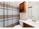 Cozy bathroom featuring a vanity with a white sink, a wooden cabinet, and a patterned shower curtain at 9155 W Portland Ave, Littleton, CO 80128