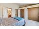 Bedroom featuring closet doors and a view of the bathroom; the bed is neatly made with blue accents at 9155 W Portland Ave, Littleton, CO 80128