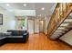 Sunlit living room featuring wood floors, a modern black couch, and open access to the staircase at 9155 W Portland Ave, Littleton, CO 80128