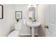 Cozy powder room featuring a pedestal sink, an oval mirror, and light neutral colors at 1034 S Williams St, Denver, CO 80209