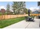 Spacious backyard with lush green grass, wood fence, patio with outdoor table and chairs, and mature trees at 10618 W Layton Pl, Littleton, CO 80127