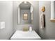 Stylish half-bathroom featuring a rounded mirror, gold fixtures, and clean, modern design at 10618 W Layton Pl, Littleton, CO 80127