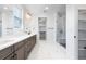 Bright bathroom featuring double vanity, marble floors, walk-in shower, and a walk-in closet at 8864 Moonshimmer Trl, Littleton, CO 80125