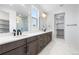 Bright bathroom featuring double vanity, marble floors, walk-in shower, and a walk-in closet at 8864 Moonshimmer Trl, Littleton, CO 80125