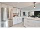Open-concept kitchen featuring white cabinets, stainless steel refrigerator, and an open design leading to the living area at 4853 S Crystal St, Aurora, CO 80015