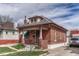 Quaint brick home featuring a covered front porch, landscaped garden, and classic architectural details at 2421 W 38Th Ave, Denver, CO 80211