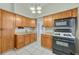 Traditional kitchen with wooden cabinets, tile backsplash, and modern appliances including a microwave and gas stove at 2421 W 38Th Ave, Denver, CO 80211