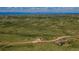 Aerial view of a house situated amongst beautiful fields and winding roads in a green, open landscape at 29333 Rawhide Ct, Elizabeth, CO 80107