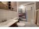 Bathroom featuring shower-tub combo, decorative wallpaper, and storage shelf at 10042 Buena Vista Dr, Conifer, CO 80433