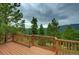 Spacious wooden deck with wooden railings surrounded by towering trees and scenic mountain views at 10042 Buena Vista Dr, Conifer, CO 80433