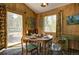 Charming dining area with wood paneling, a round table with seating, and scenic outdoor views at 10042 Buena Vista Dr, Conifer, CO 80433
