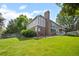 Expansive backyard featuring lush green lawn, mature trees, and a charming brick home with a swing at 4161 W Lake Cir, Littleton, CO 80123