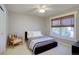 Cozy bedroom with a ceiling fan, a bed with a grey and white quilt, and a chair by the window at 22921 E Euclid Cir, Aurora, CO 80016