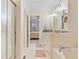 Well-lit bathroom featuring tile flooring, modern vanity, soaking tub, glass shower, and view into the bedroom at 3000 E 112 Ave # 102, Northglenn, CO 80233