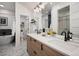 Modern bathroom with double sinks, wood-look vanity, and a view into shower/tub room at 2998 S Adams St, Denver, CO 80210