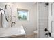 Bright bathroom featuring white quartz countertop, round mirror, and subway tiled shower with black hardware at 2998 S Adams St, Denver, CO 80210