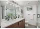 Modern bathroom with dual sinks, wood cabinets, updated fixtures, and a walk-in shower at 2998 S Adams St, Denver, CO 80210