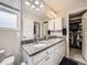 Bathroom showcasing a granite countertop, double sink, large mirror, and a view into the walk-in closet at 3744 Celestial Ave, Castle Rock, CO 80109