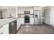 Modern kitchen with stainless steel appliances, gray countertops, white cabinets, and hardwood floors at 11896 W 107Th Ave, Westminster, CO 80021