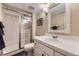 Well-lit bathroom featuring a shower with glass doors and a white tiled vanity with a decorative mirror at 5988 E Jamison Ln, Centennial, CO 80112