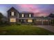 Charming two-story home featuring a well-manicured lawn, brick accents, and a two-car garage at dusk at 5988 E Jamison Ln, Centennial, CO 80112