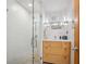 Modern bathroom with walk-in shower and stylish vanity with natural wood drawers at 3895 Chimayo Rd, Littleton, CO 80123