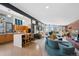 Open-concept living room with a modern kitchen, curved sofa, and floor-to-ceiling windows offering bright, natural light at 3895 Chimayo Rd, Littleton, CO 80123