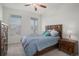 Well-lit bedroom with two windows, ceiling fan, wooden headboard, and wood nightstand at 8852 Farmdale St, Firestone, CO 80504