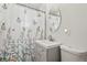 Bathroom with a floral shower curtain, gray vanity, oval mirror, and white toilet at 1070 S Newton St, Denver, CO 80219