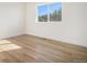 Bright bedroom with wood-look floors and window offering a view of trees at 10694 Camelot Dr, Franktown, CO 80116