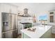 Modern kitchen with stainless steel appliances, white countertops, and a green island at 10694 Camelot Dr, Franktown, CO 80116