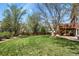 Expansive backyard with lush green grass, mature trees, and a relaxing deck area at 9536 W Avalon Dr, Littleton, CO 80127