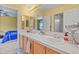 Bathroom featuring double sinks, wood cabinets, tiled backsplash, and a view into an adjacent bedroom at 9536 W Avalon Dr, Littleton, CO 80127