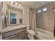 Modern bathroom featuring a granite countertop vanity and tiled shower-tub with small windows at 17910 E 54Th Ave, Denver, CO 80249