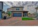 Two-story home featuring a blue garage door and quaint front lawn on a brick driveway at 17910 E 54Th Ave, Denver, CO 80249