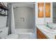 Bright bathroom featuring a shower over bath, built-in storage and a sink with oak vanity at 2244 Fenton St, Edgewater, CO 80214