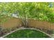 Serene backyard with green grass, mature tree, rock garden, and wood fence at 5400 Heatherton Ln, Highlands Ranch, CO 80130