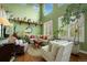 Sunlit living room with soaring ceilings, showcasing a cozy seating area and decorative shelving at 5400 Heatherton Ln, Highlands Ranch, CO 80130