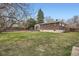 This backyard features green grass, a brick house, and mature trees on a sunny day at 798 Xenophon St, Lakewood, CO 80401