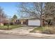 Single-story brick home features an attached two-car garage, mature trees, and a well-maintained front yard at 798 Xenophon St, Lakewood, CO 80401