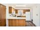 Well-lit kitchen with wooden cabinets, countertop bar, and dark wood-look flooring at 798 Xenophon St, Lakewood, CO 80401